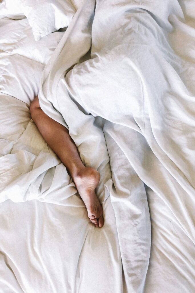 a woman sleeping peacefully in her bed white blankets