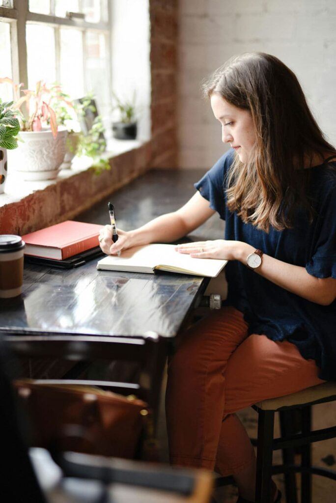 a woman writing on her notebook