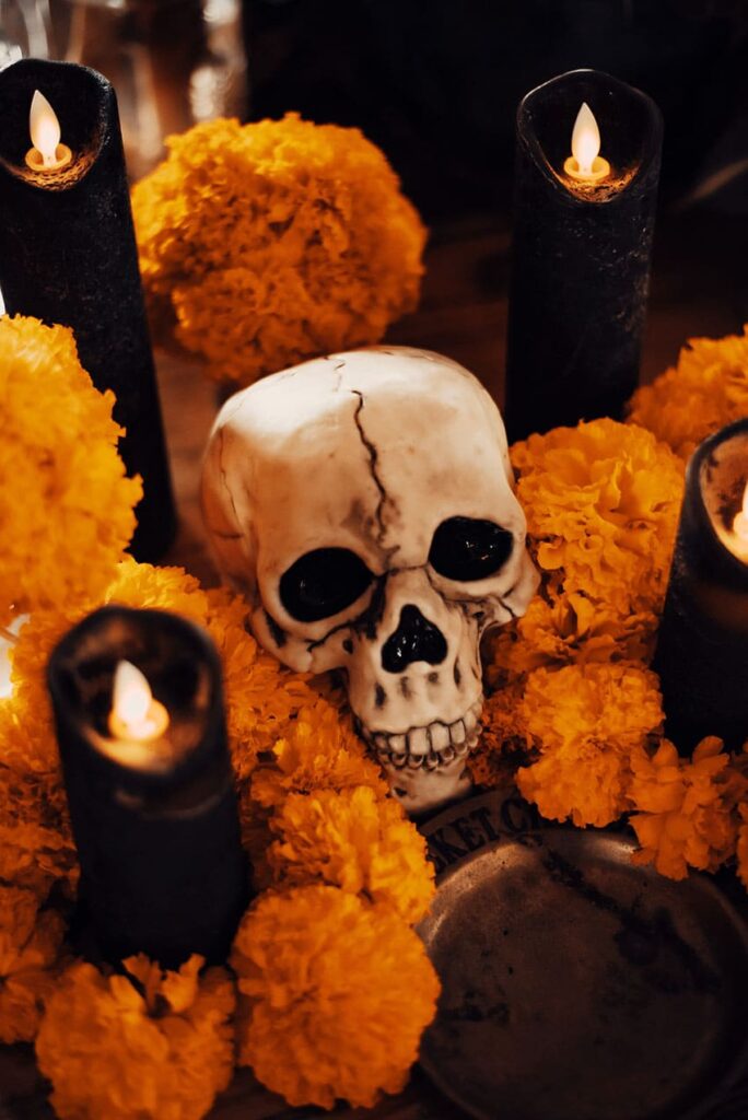a fake skull surrounded by candles and orange flowers