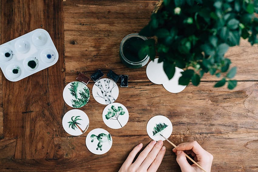 a woman painting wood items with plant patterns