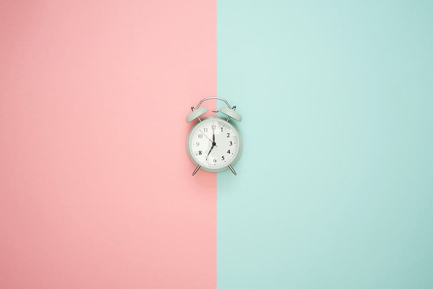a clock over a pink and light blue backround
