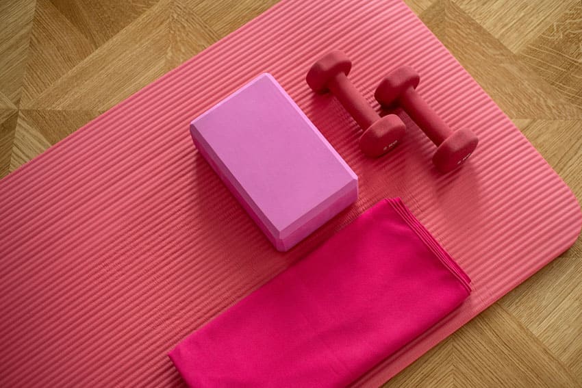 two red dumbells on a pink yoga mat-startin small helps you stop procrastinati your workouts