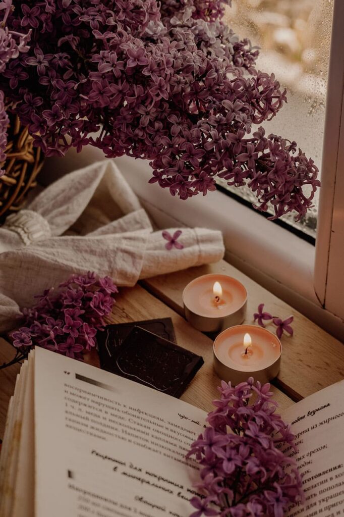 a book, two tea candles and pink flowers cozy setting