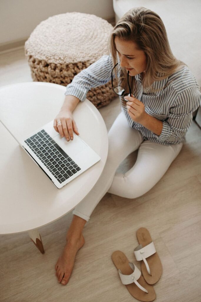 a happy woman working in her living room with a laptop neutral colors