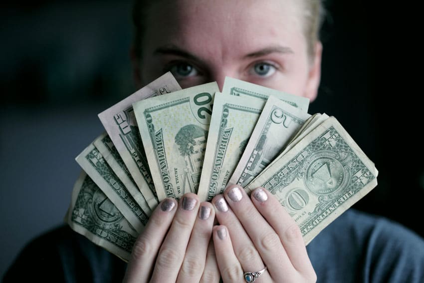 blonde-woman-holding-bills-in-front-of-her-face how to sell low content books on etsy