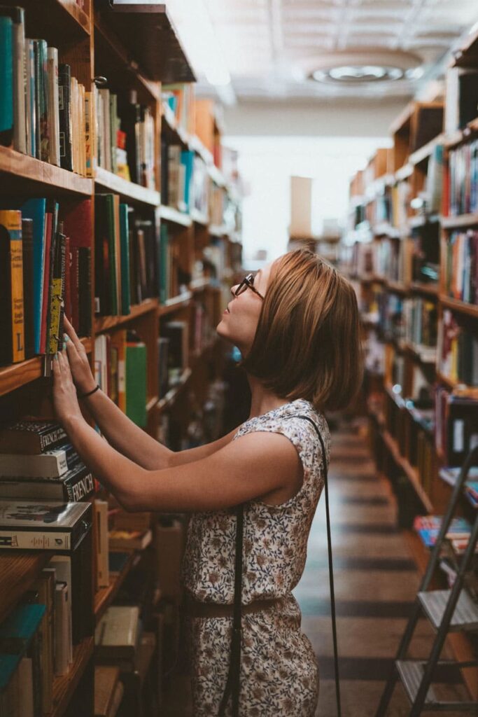 a young woman searching for a book in a public library