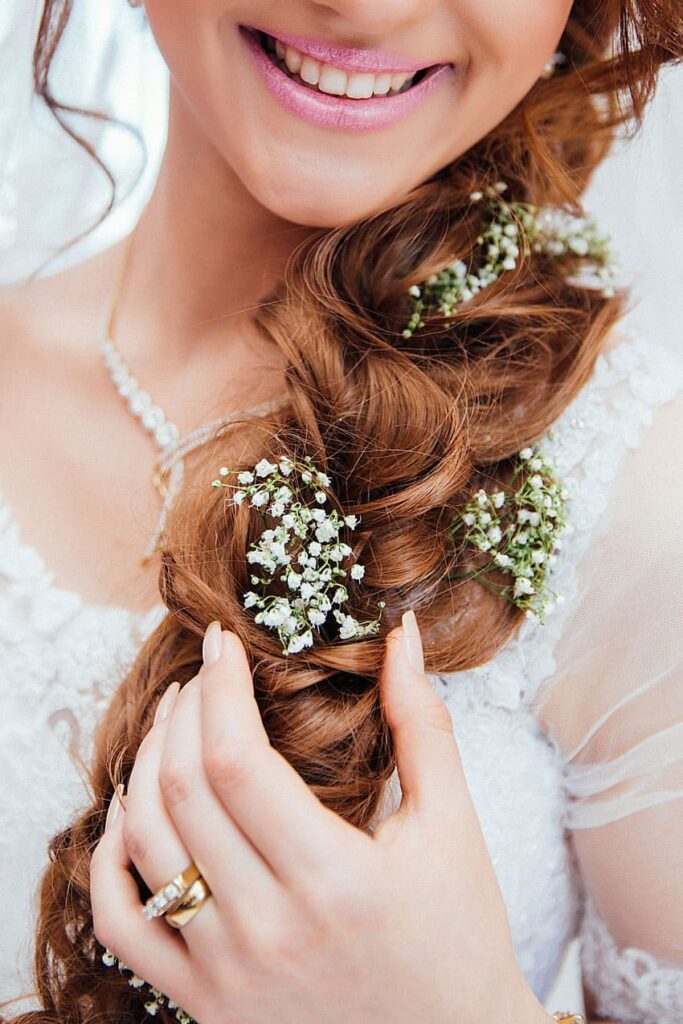 a woman wearing a wedding dress and showing her hairdo with braids and flowers