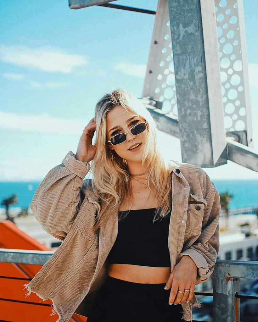 young blonde girl posing for a photo, city background influencer as one of the best beauty side hustles