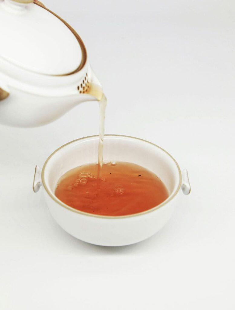 a white kettle pouring tea into a white tea cup