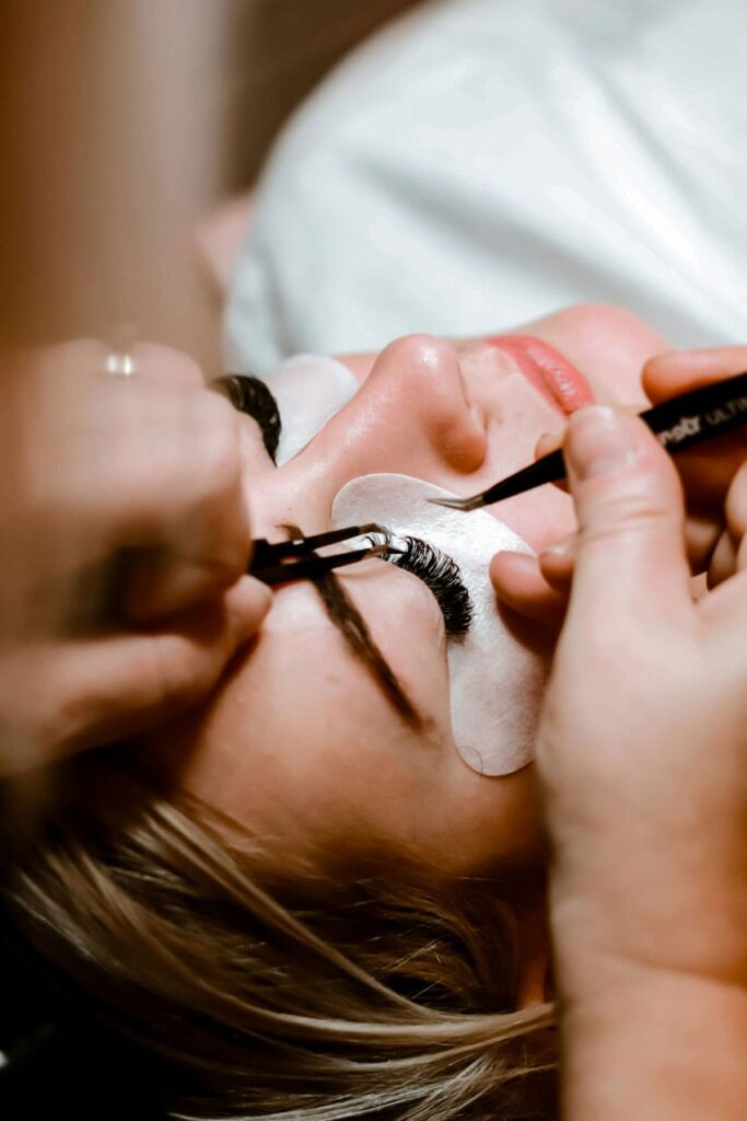 a woman applying lash extension on a another's woman face