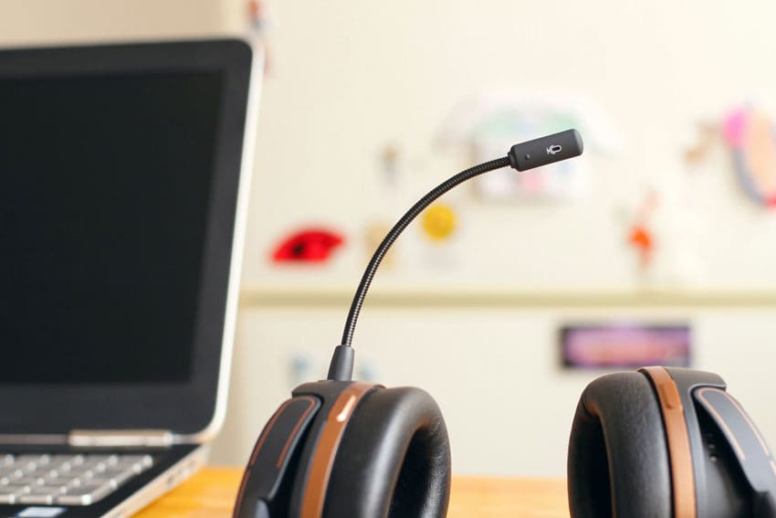 headphones with microphone over an office desk with personal laptop next to it