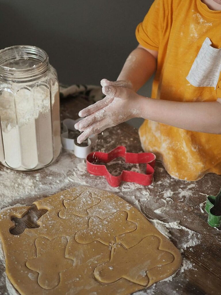 a kids cutting cookies from dough with gingerman cutter