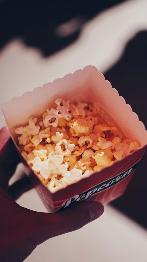 a person holding a bag of popcorn - cheap fall activities for adults