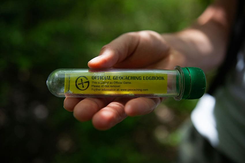 a person holding a geocaching container