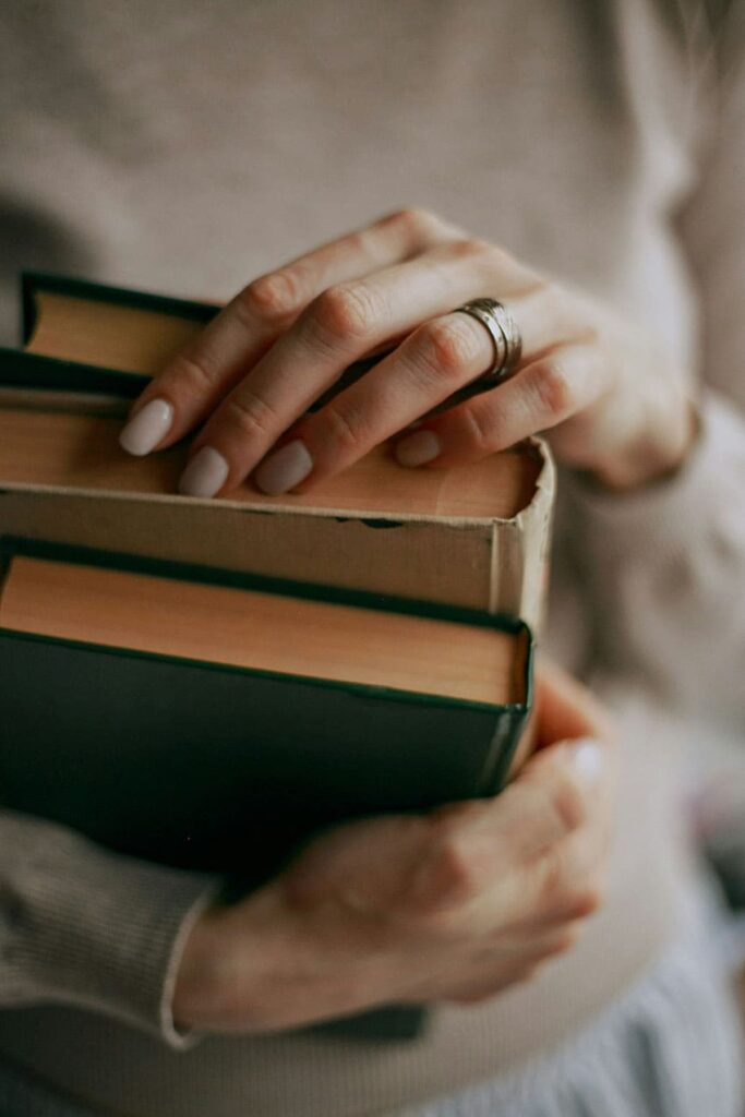 a woman holding a pile of books - cheap fall activities for adults