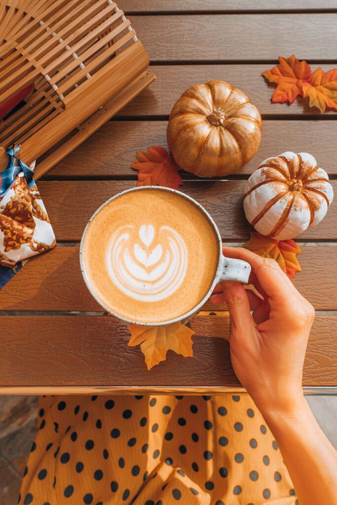 a woman holding a pumpkin spice coffee cup