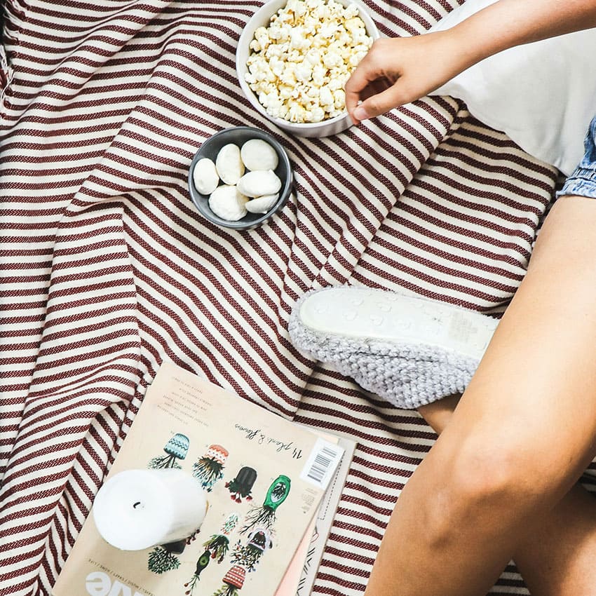 a woman wearing pajamas and eating popcorn