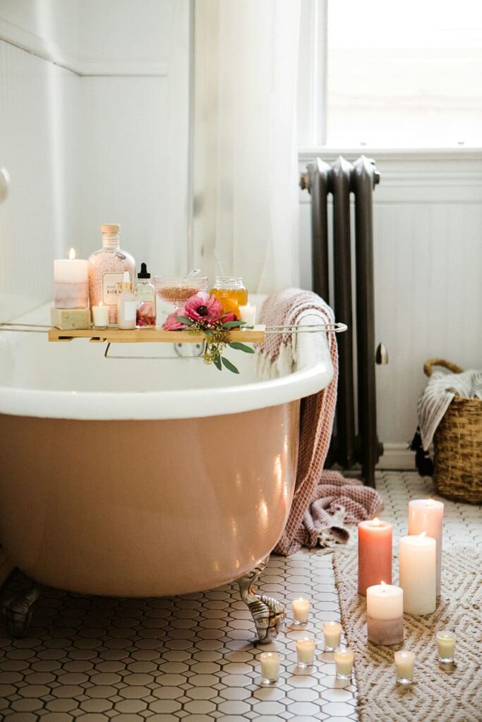 bathtub with candles, flowers, and skincare products