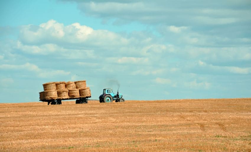 tractor pulling a wagon loaded with hay in the countryside