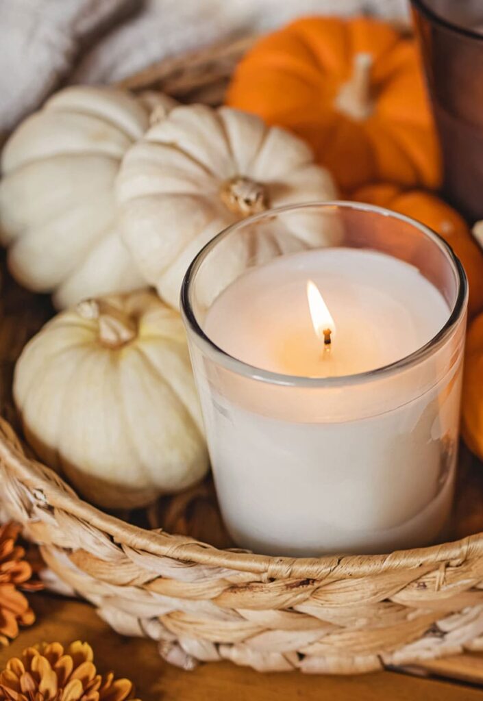 a jute container with decorative pumpkins and a candle