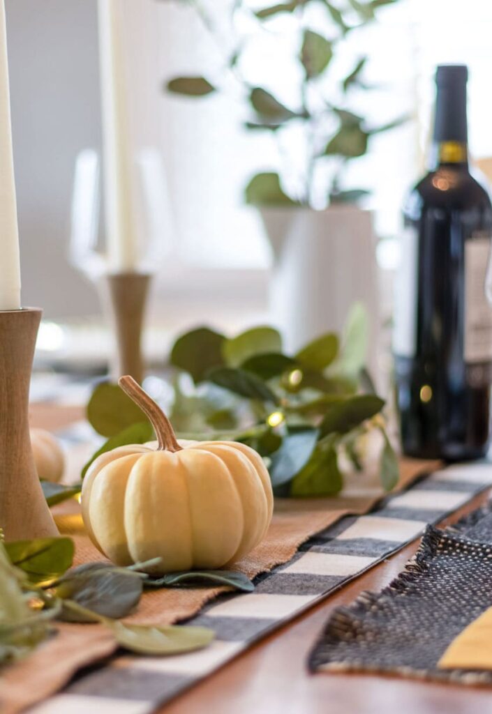 a burlap runner along a kitchen table with centerpiece and other decor items