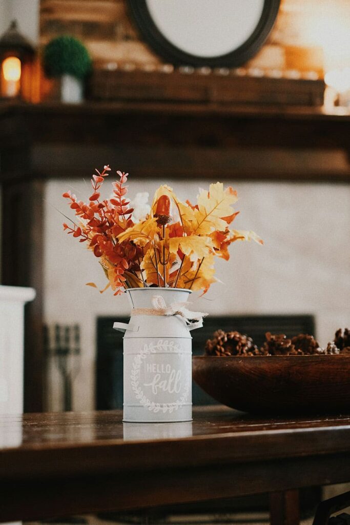 an orange and yellow dried flower bouquet in white vase