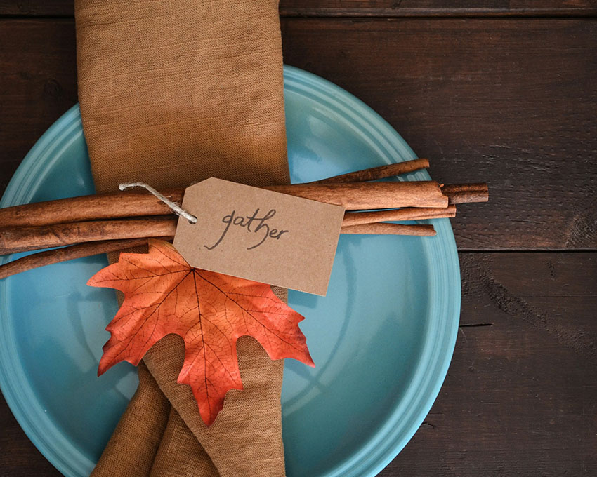 a DIY napkin ring made out of wooden stick a faux leaf and message tag saying gather