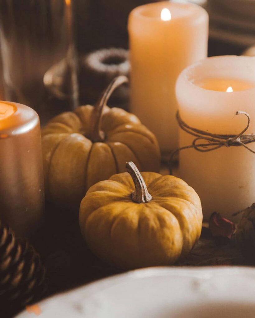 white candles decorated with brown ribbons and brown pumpkins