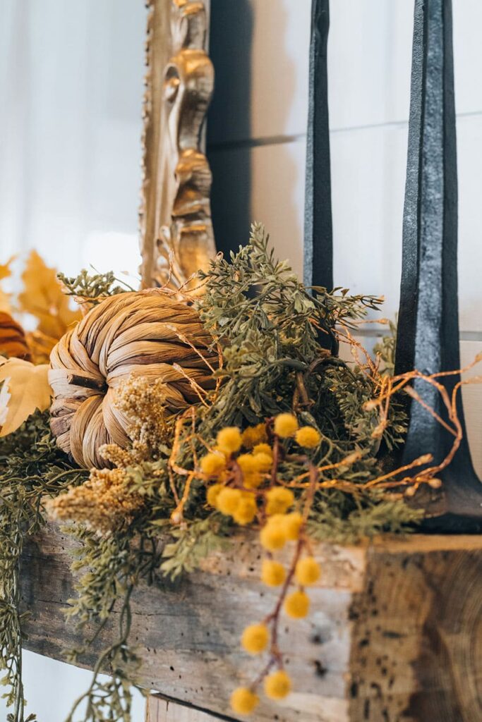 a garland made out of natural items like dried plants and a bown pumpkin