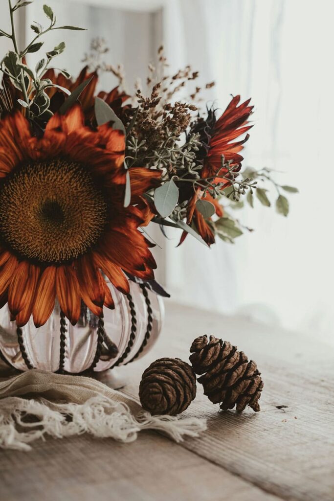 a vase with dried sunflowers and pinecones